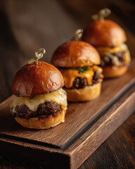 Three sliders with cheese on a wooden board