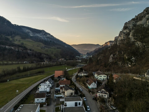 Aerial view of a picturesque village with tranquil houses nestled in a serene valley surrounded by mountains at sunset, Oensingen, Solothurn, Switzerland.