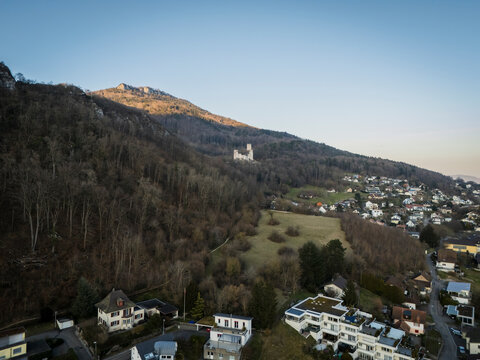 Aerial view of the picturesque Castle Neu Bechburg amidst a beautiful landscape of mountains, forests, and residential homes, Oensingen, Solothurn, Switzerland.