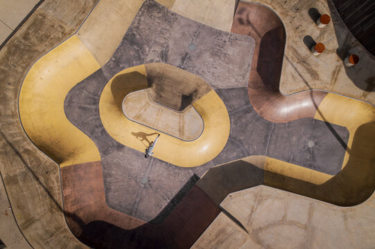 Aerial view of dynamic skatepark with skateboarders and intricate concrete patterns, Halls Head, Australia.