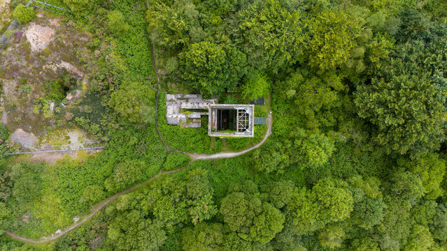 Aerial view of the ruins of a cornish mining heritage site surrounded by lush forest and greenery, Gunnislake, United Kingdom.