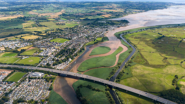 Aerial view of the scenic river Exe meandering past the M5 bridge and picturesque homes in the countryside, Exeter, England.