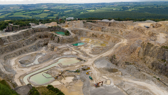 Aerial view of industrial quarry with heavy machinery and excavation pits, St Ann's Chapel, Gunnislake, England.