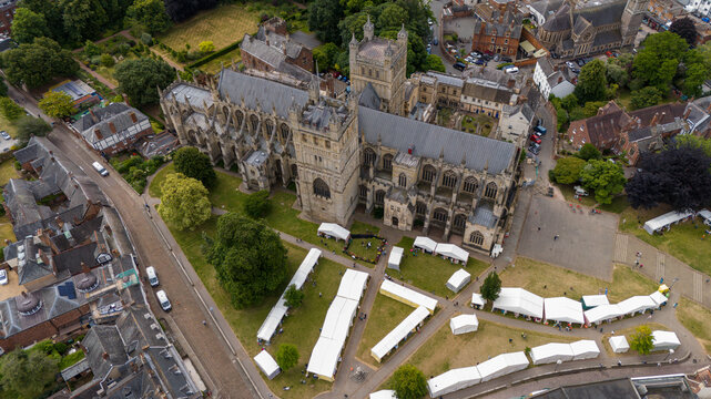 Aerial view of exeter cathedral surrounded by trees and event tents in a vibrant cityscape, exeter, united kingdom.