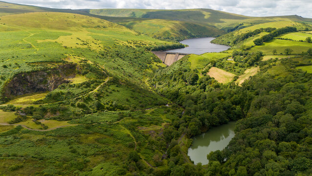 Aerial view of lush hills and a tranquil valley with a river and lake, Meldon, Okehampton, England.