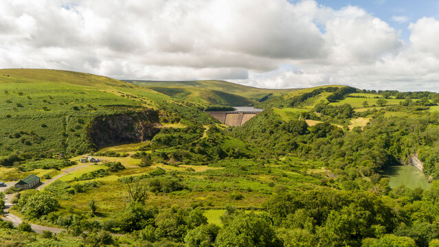 Aerial view of lush Meldon reservoir surrounded by serene hills and clear sky, Okehampton, England.