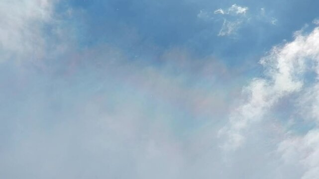 Blue sunny sky, sunlight, pollen from flowering trees flying in air, moving white clouds Altocumulus and Cirrocumulus with colorful Cloud iridescence, Irisation with pearl colors. Topic: allergens