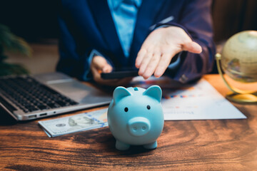 Businessperson Advising on Financial Planning with Piggy Bank, Laptop, and Currency on Wooden Table