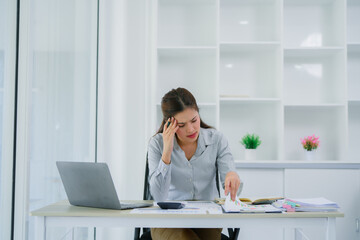 Exhausted business woman in her office with head in hands, she is having a bad headache, overwork...