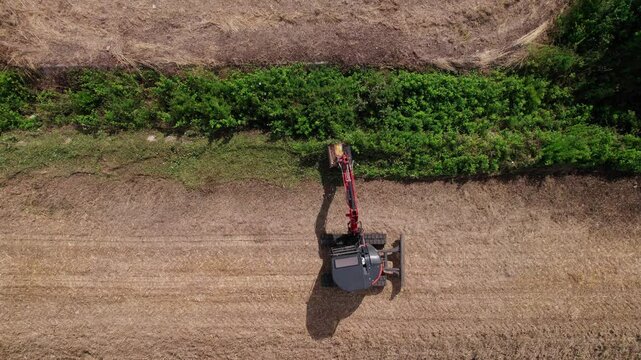 View of mini excavator mowing canal slope