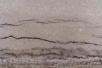 Cracks in the asphalt road surface are caused by poor road construction and failure to compact the road surface before laying the asphalt. The background of the asphalt on the road surface has cracks.