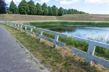 Serene pond with fence and tree-lined path