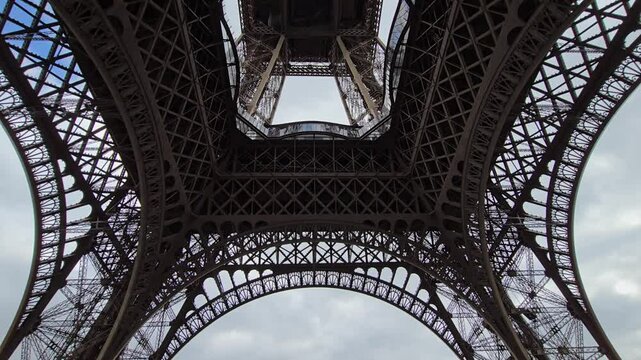 Metal structure of the Eiffel Tower with cloudy sky in Paris