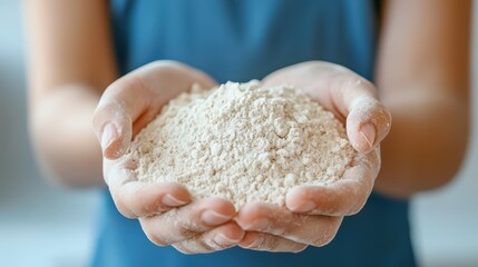Person holding powdery flour in hands with close-up focus on texture and detail of baking ingredient