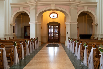 Fototapeta premium A large church with a long aisle of pews and a large altar. The pews are empty and the altar is covered in flowers