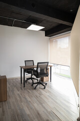 A compact glass meeting space with two black chairs and a round table, creating a sleek and modern environment for private discussions and teamwork.

