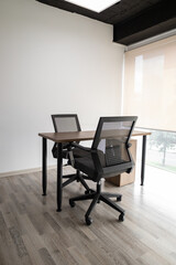 A stylish glass-enclosed meeting room featuring two black chairs and a small table, designed for professional discussions and private teamwork sessions.

