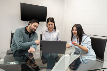 A group of three women gathered around a laptop at a table, actively exchanging ideas, representing teamwork, modern work culture, and problem-solving.

