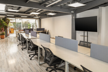 A bright and open coworking area featuring long tables and multiple chairs, designed for collaboration, productivity, and flexible work in a contemporary environment.

