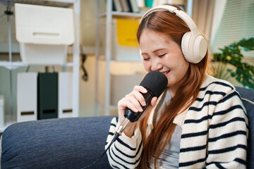 Young woman podcast host smiling with microphone and headphones at home