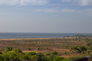 Naklejka premium Beautiful landscape captured from Mahabalipuram view point, pointing towards the seashore along with trees, sky and sea together with browning land
