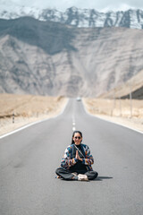 Joyful woman celebrating freedom on the open road through the Leh Ladakh mountains, where adventure, nature, and high-altitude serenity converge under the clear Himalayan skies