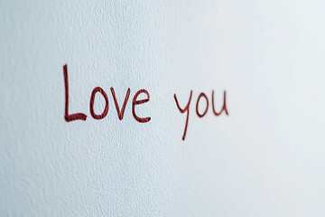 The message "Love you" is written in red on a white background, possibly on a wall. It has a casual feel.
