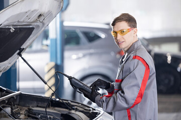 Obraz premium Man is measuring battery power of suv car by battery tester at garage service