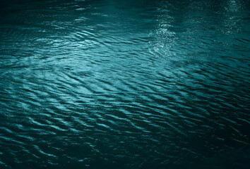 Ripples and reflection of light, blue green water background with space for design