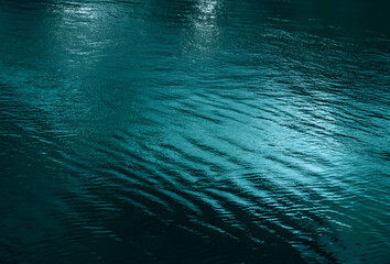Ripples and reflection of light, green water surface background with space for design