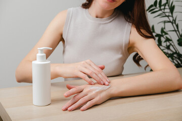 Female hands applying moisturizer cream or lotion. Hand skin care, treatment skin care body concept. Routine in the morning