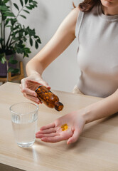 A woman holds omega-3 fish oil capsules. Healthy lifestyle, prevention and treatment of diseases. The woman takes and drinks dietary supplements and vitamins for skin, nails and hair. 