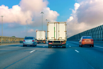 Mini truck driving on highway surrounded by other cars on sunny evening. Small shipment cargo courier truck moving fast motorway city urban suburb. Business distribution logistics express service