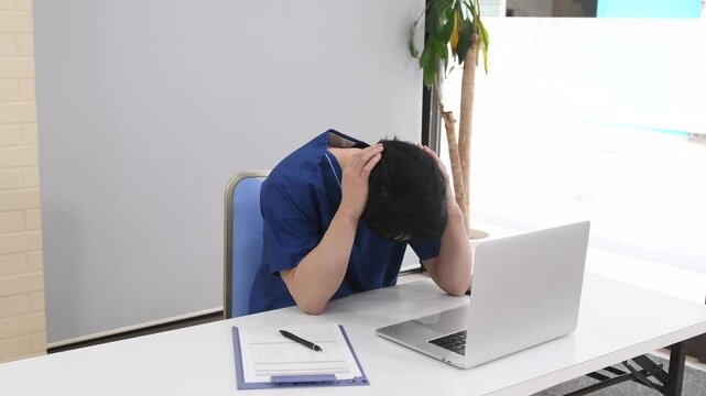 PCの前で困り顔で悩む医療従事者の男性