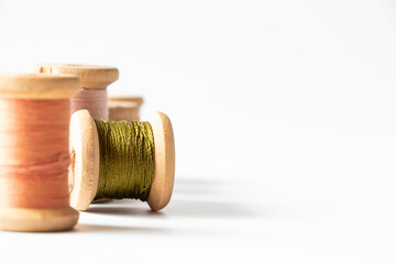 Wooden spools of threads of different colors on white background, handicraft, sewing