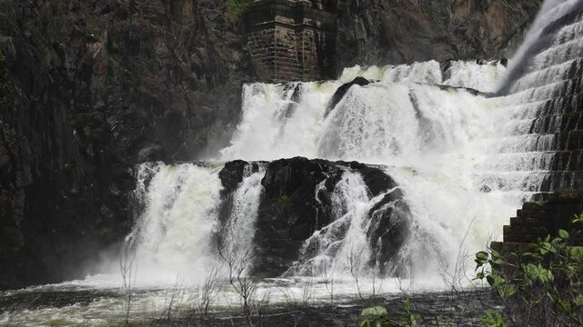 water cascading down waterfall at croton dam (man made and natural drinking water reservoir) westchester new york landmark with old bridge (tourism travel hiking destination) nature landscape