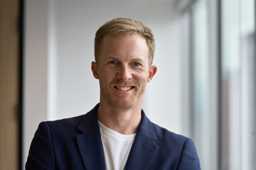 Portrait of young happy professional business man, smiling corporate leader in his 30s, confident businessman executive manager wearing white suit looking at camera in office. Headshot, close up