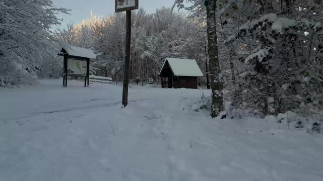 Toma din&aacute;mica a ras del suelo nevado en el Parque Nacional Una. El dron se desliza r&aacute;pidamente en direcci&oacute;n a la caseta del guardabosques, mientras todo el paisaje circundante permanece nevado.