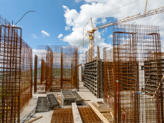 Construction site with rebar framework and a crane against a blue sky with clouds symbolizing progress and building the future