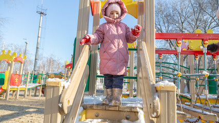 Two little girl playing on the playground on a winter day