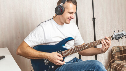 Guitarist. Focused man in headset enjoy creative hobby play electric guitar at home. Man musician...