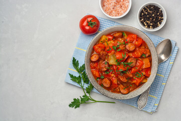 Traditional Hungarian dish Lecho or Lecso or Letscho. Stew with peppers, tomatoes, onions and sausages in bowl on concrete background.
