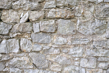Fototapeta premium Close up of a gray stone wall with varied shapes and sizes bound together with mortar creating a textured and rustic backdrop