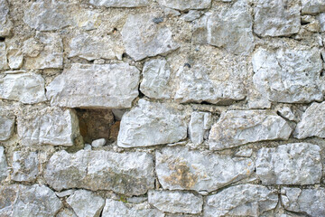 Stone Wall Texture: Close up of a weathered light gray rock wall with varied shapes and sizes of stones