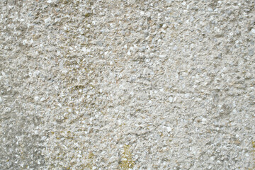 A close up of a weathered concrete surface with small pebbles and granular texture creates a...