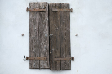 Weathered wooden shutters on a white stucco wall showing signs of age and rustic charm a simple yet captivating architectural element
