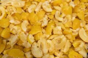 A close-up image showing chopped frozen quinces in various sizes, highlighting their yellow color and icy texture, ideal for culinary use.