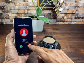Smartphone displaying suspected spam call with coffee on a wooden table