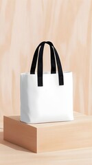 Minimalist white tote bag with black handles, displayed on a light wood block against a neutral backdrop