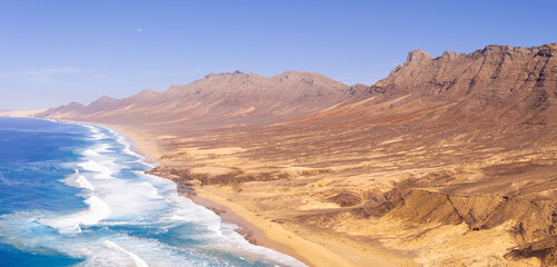 Beautiful high aspect aerial panoramic view of Cofete Beach and the majestic volcanic mountain backdrop in Fuerteventura Canary Islands Spain